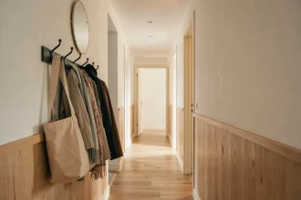 Couloir long et étroit d'appartement moderne avec porte-manteau mural en métal mat noir et miroir ovale au-dessus