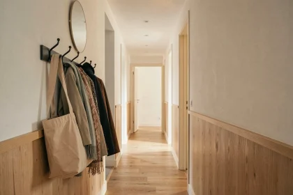 Couloir long et étroit d'appartement moderne avec porte-manteau mural en métal mat noir et miroir ovale au-dessus