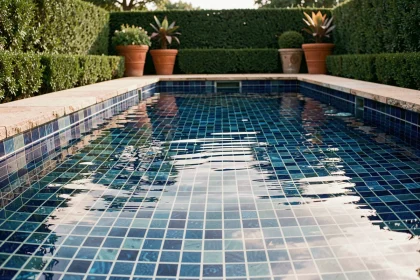 Piscine extérieure avec revêtement en mosaïque de verre bleu cobalt, vue en contre-plongée au niveau de l'eau dans un jardin contemporain